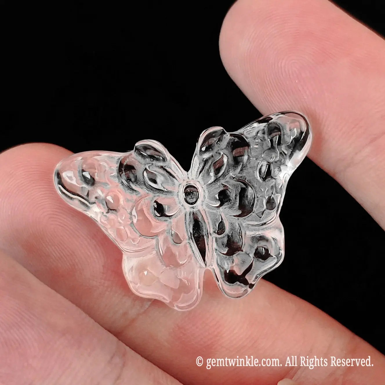Mini precision carved clear quartz butterfly figurine displayed on open fingers for accurate 3cm size scale reference