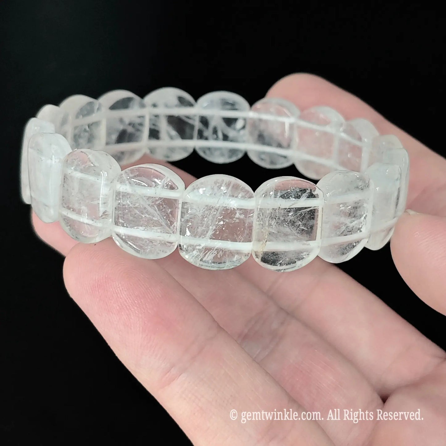Side profile of natural clear quartz smooth rectangular bead bracelet showing glossy surface reflections under studio lighting