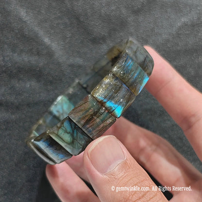 Close up view of grey moonstone rectangular bead cuff showing natural mineral textures and teal light reflection