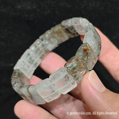 Hand displaying an opaque green phantom quartz smooth block tile stretch bracelet highlighting subtle green specks on white quartz