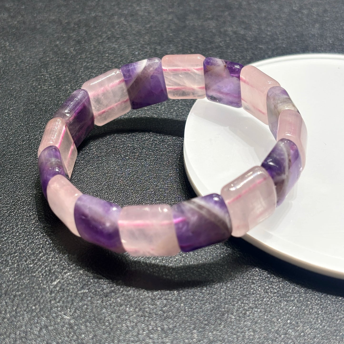 Close-up side view of dual-tone rectangular slab bracelet on white dish edge, highlighting faceted edges and natural inclusions
