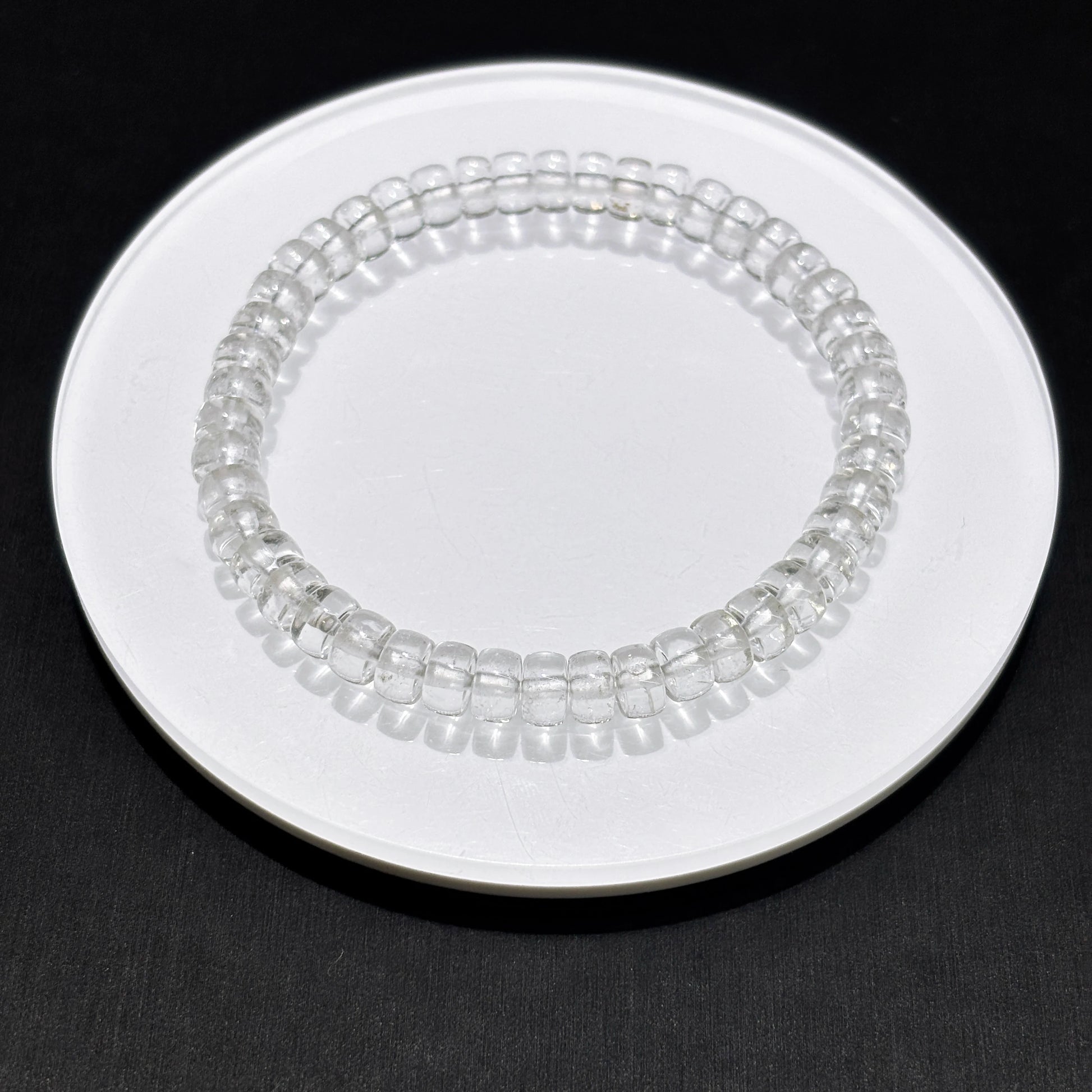 Clear quartz disc bead bracelet on white ceramic plate, clean product photography