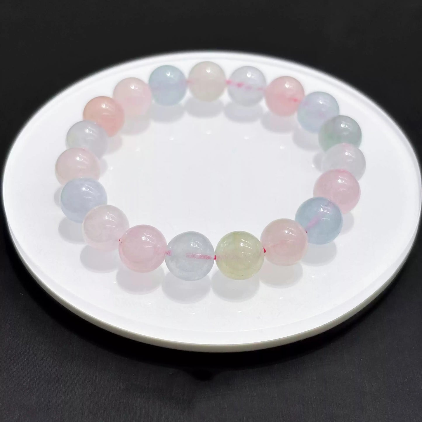 Single strand of natural morganite bracelet laid flat on white dish, smooth round beads, even lighting, minimalist aesthetic.
