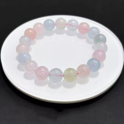 Single strand of natural morganite bracelet laid flat on white dish, smooth round beads, even lighting, minimalist aesthetic.