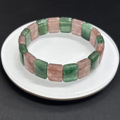 Single natural strawberry quartz rectangular slab bracelet on white plate, studio lighting, eco-friendly gemstone jewelry