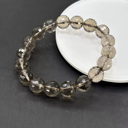 Smoky quartz faceted bracelet placed beside smartphone to show real-world size and minimalist aesthetic