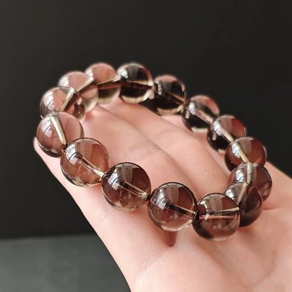 Smoky quartz handchain held in palm showing round bead shape