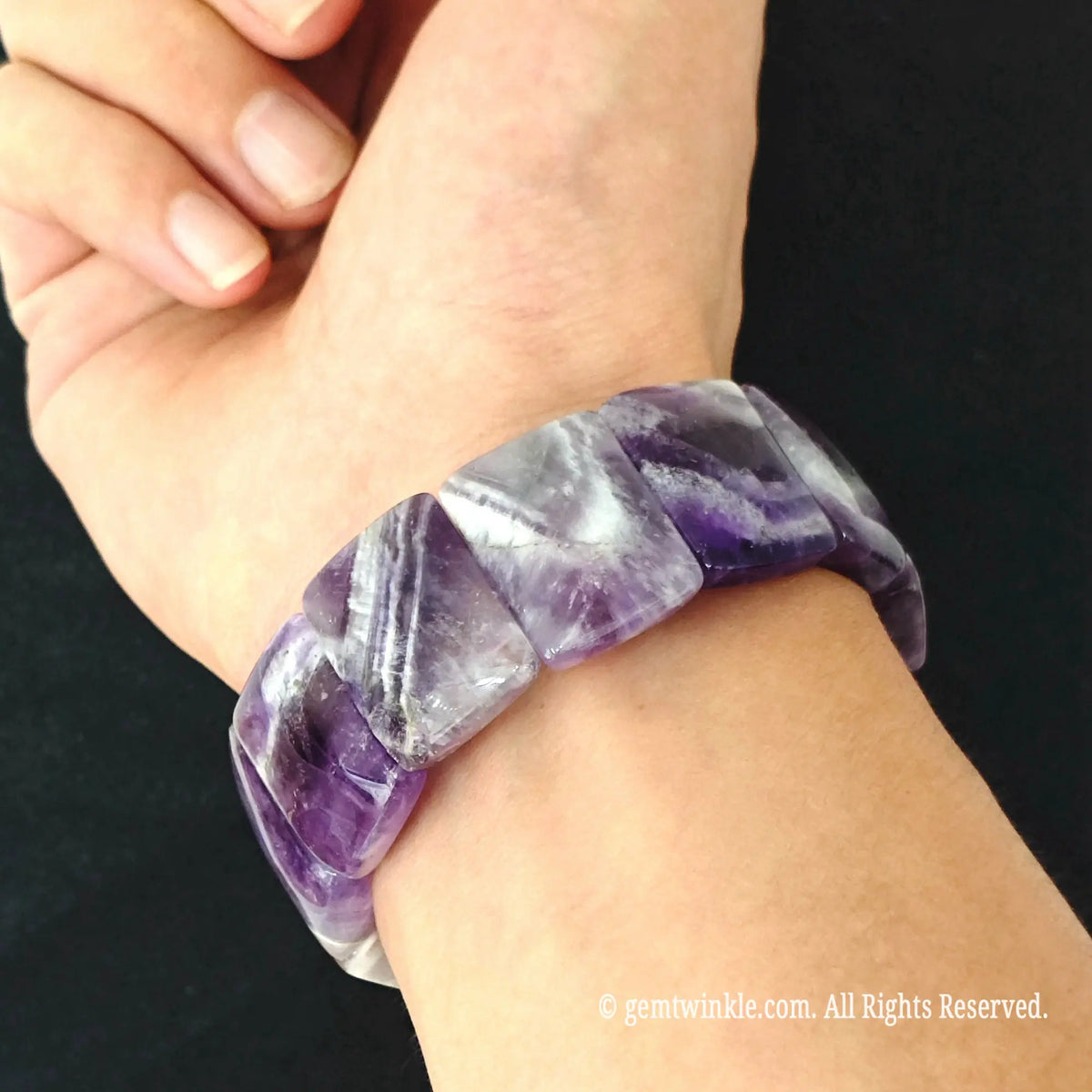 Close up view of stacked chevron amethyst smooth segment bracelets worn on wrist showcasing deep purple and white crystal bands