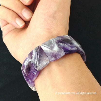 Close up view of stacked chevron amethyst smooth segment bracelets worn on wrist showcasing deep purple and white crystal bands