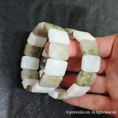 Close up view of stacked golden jadeite quartz smooth segment bracelets worn on wrist showcasing creamy white and mossy green quartzite matrix