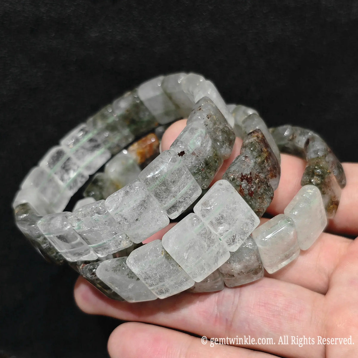 Close up view of stacked opaque green phantom quartz smooth block tile bracelets worn on wrist showcasing opaque white quartz matrix and mossy specks