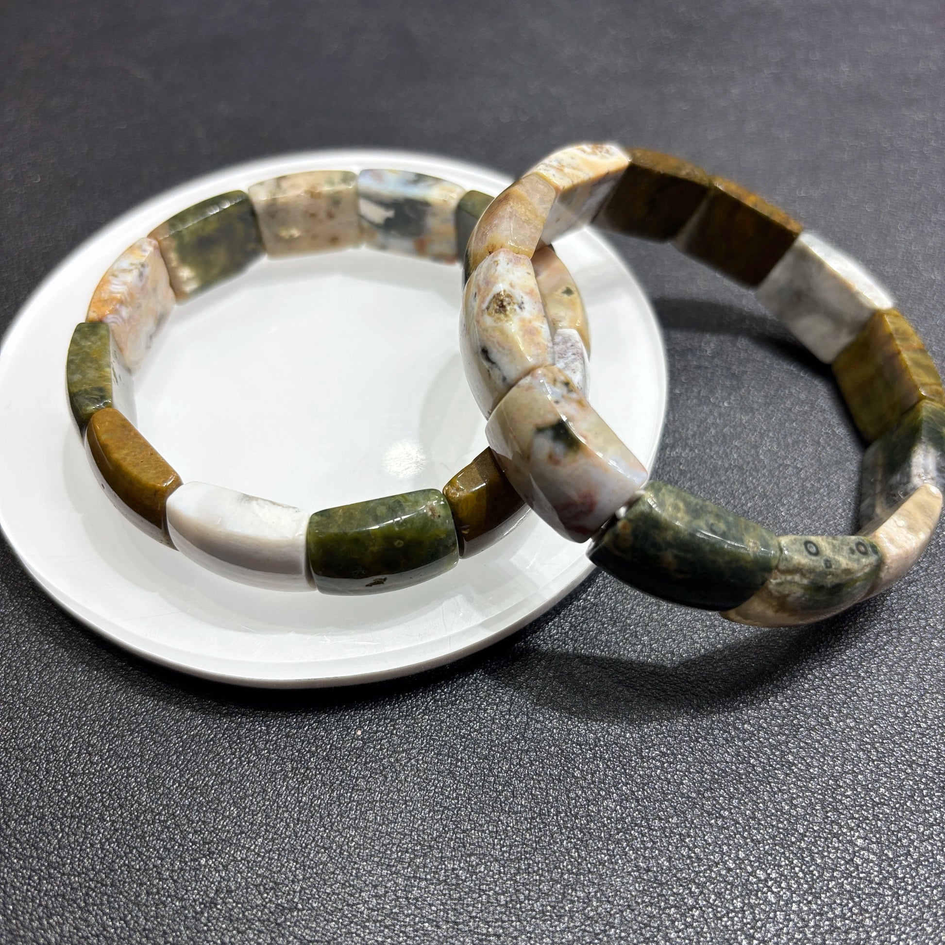 Two natural ocean jasper square bead bracelets layered on ceramic dish; highlights earthy palette and stackable boho styling