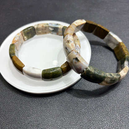 Two natural ocean jasper square bead bracelets layered on ceramic dish; highlights earthy palette and stackable boho styling