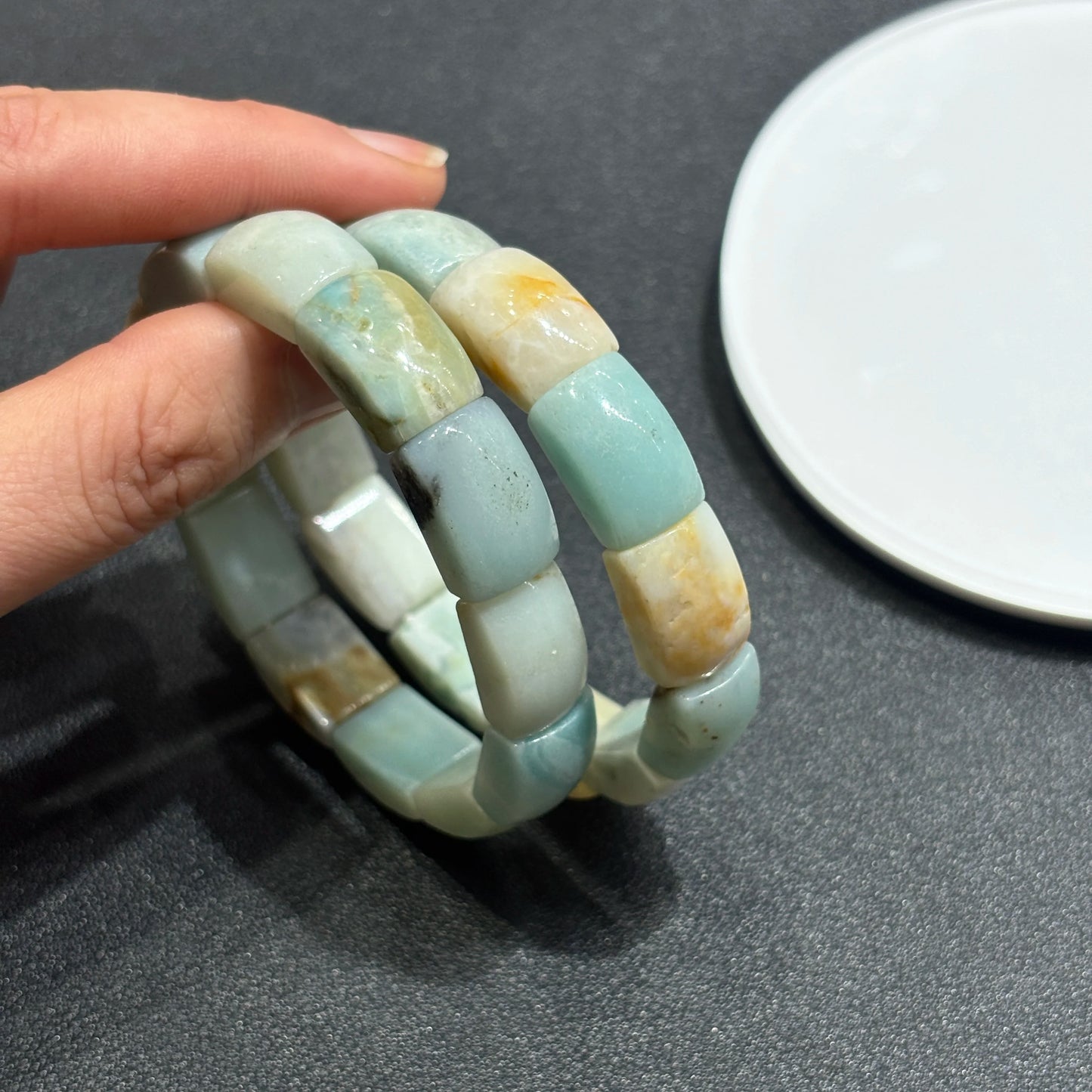 Hand holding two natural caribbean calcite square bead bracelets; shows gentle color gradient and minimalist boho styling