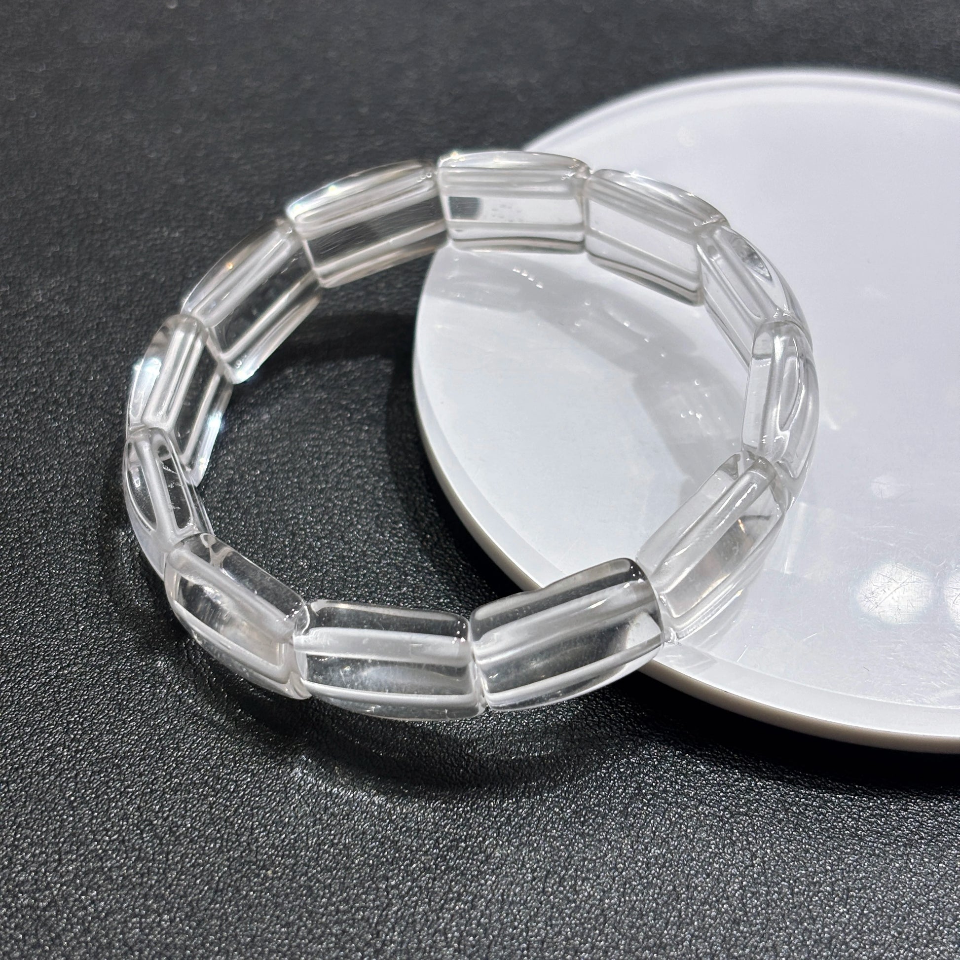 Two clear quartz square tablet bracelets layered on white ceramic dish, minimalist aesthetic stackable design