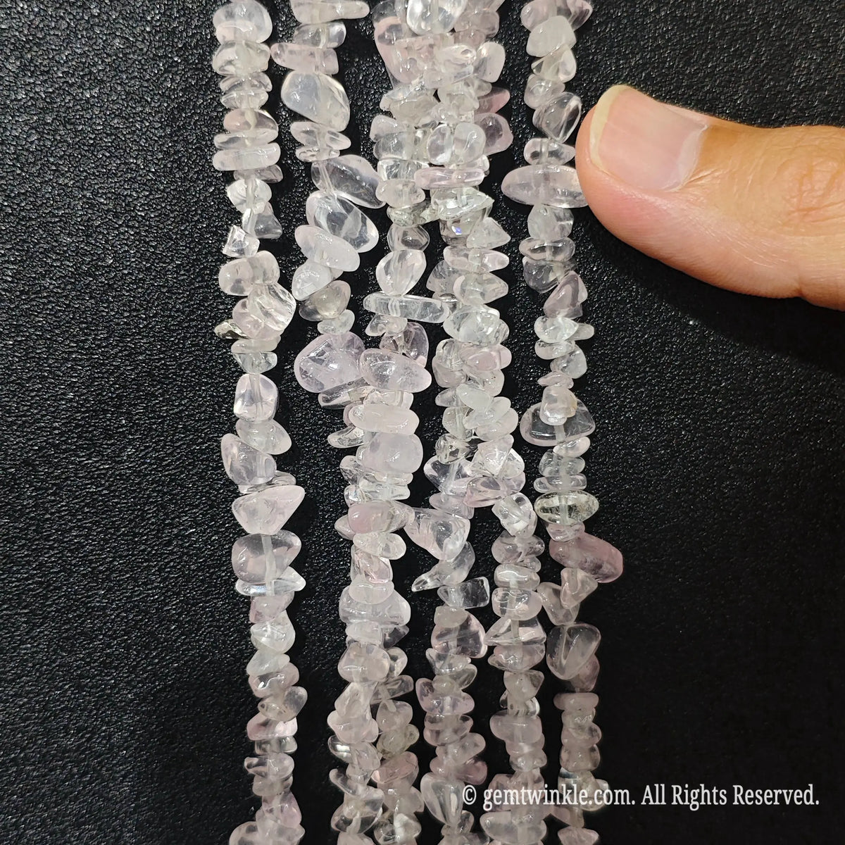 Close up hand holding natural star rose quartz stone chips displaying polished surfaces and fine drill holes