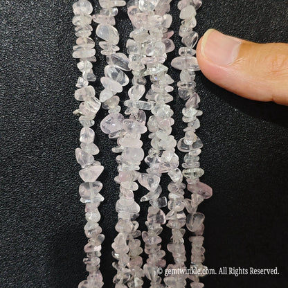 Close up hand holding natural star rose quartz stone chips displaying polished surfaces and fine drill holes