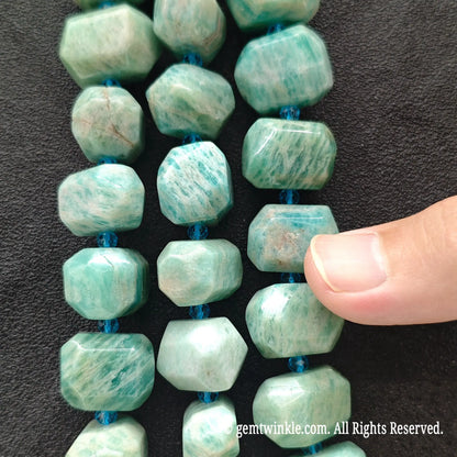 Hand holding three strands of natural green amazonite freeform faceted gemstone beads showing white feldspar striations
