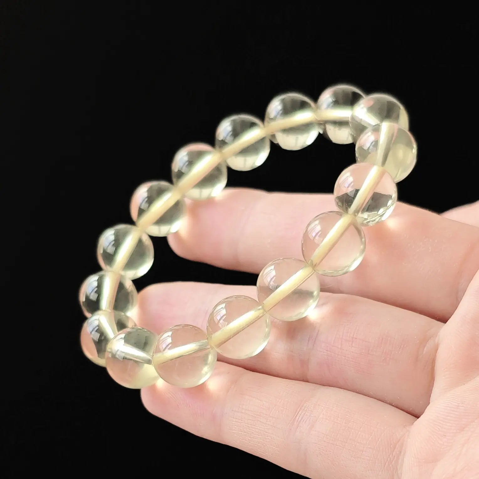 Citrine round beads stretched between fingers—secure knotting, elastic resilience, uniform bead alignment
