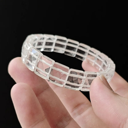 Faceted quartz beads stretched between fingers—secure knotting, elastic resilience, uniform alignment of cut faces