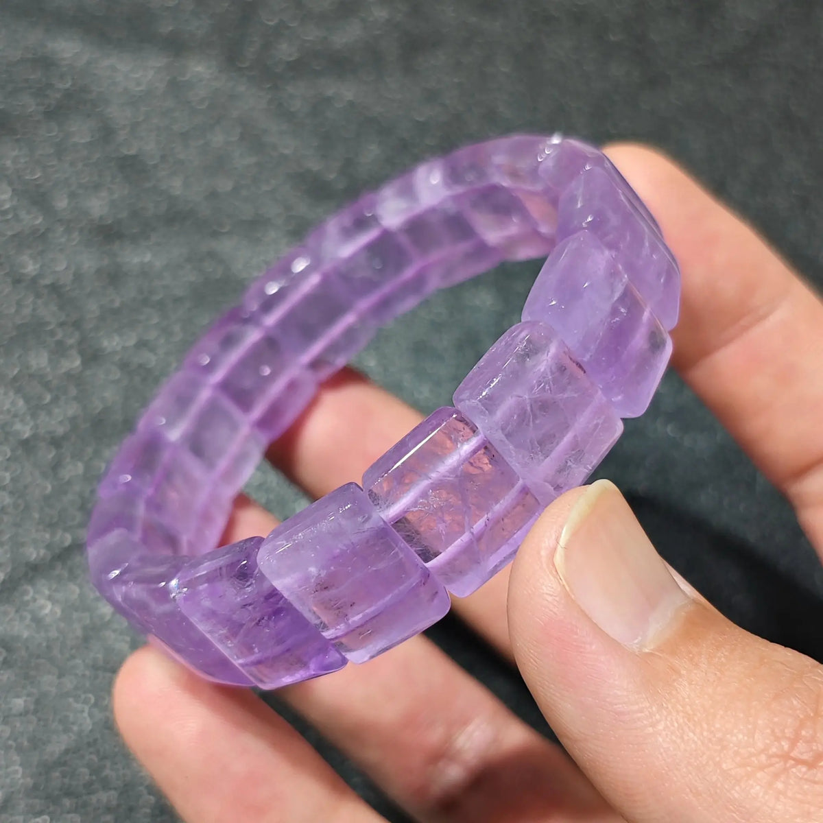 Hand displaying a translucent lavender amethyst bamboo segment stretch wristband under natural light