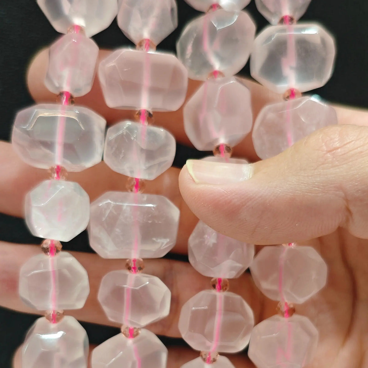 Close up perspective of multiple natural translucent rose quartz faceted freeform bead strands showing smooth polished finish