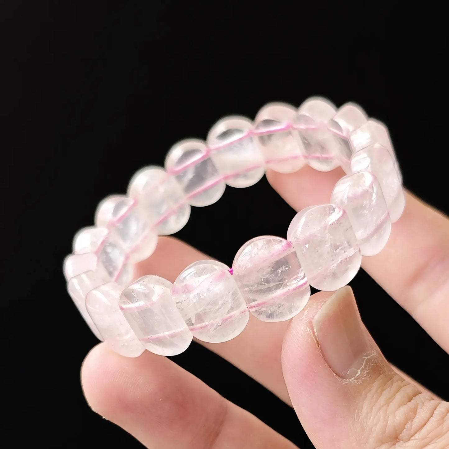 Light-pink translucent rose quartz crystal beads catching soft light, symbolizing compassion and emotional balance in modern aesthetics