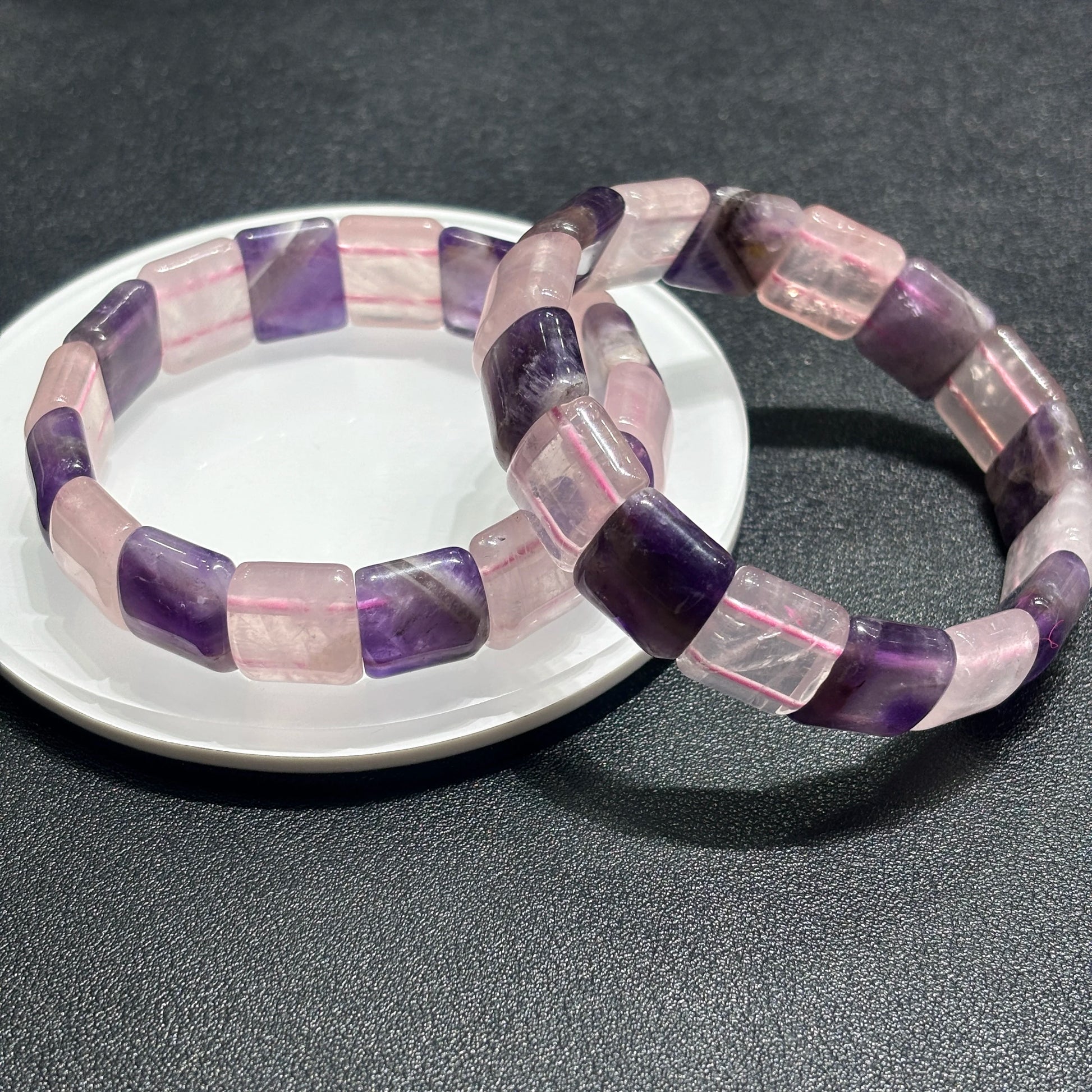 Two natural amethyst & rose quartz bracelets arranged on white ceramic plate, alternating purple-pink slab beads, mindful self-love accessory