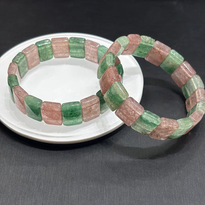 Two natural strawberry quartz stretch bracelets in pink and green slabs, displayed on white ceramic plate, gift-ready