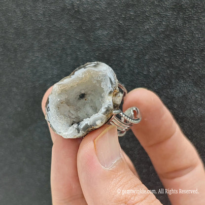 Sparkling white druzy agate cavity ring held under studio lighting showing micro quartz crystals and natural stone texture