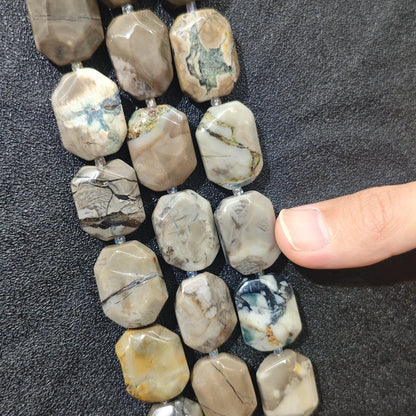 Strands of volcanic ash banded agate faceted flat slab beads displaying grey matrix and dark vein lines on dark background