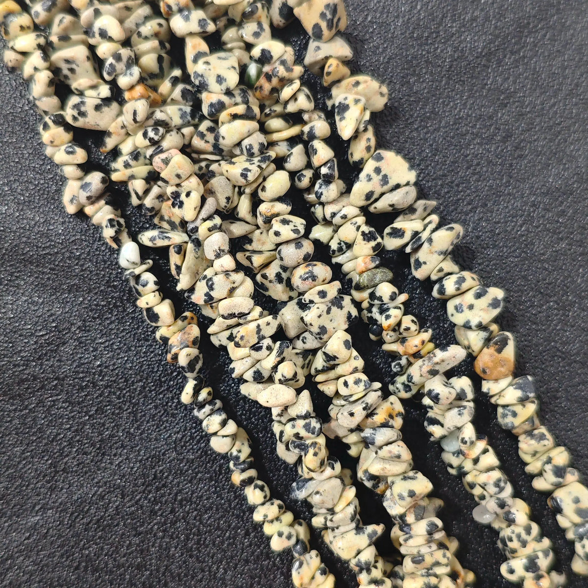 Multiple strands of natural darmatian jasper 5-10mm irregular chip beads showing cream and black spotted texture[cite: 8]