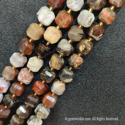 Multiple parallel strands of natural wood grain jasper soft-tumbled cube beads viewed from distance