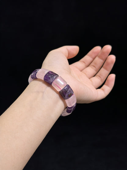 Woman wearing amethyst and rose quartz rectangular slab bracelet on wrist (19cm fit), black background, symbolic chakra jewelry for women