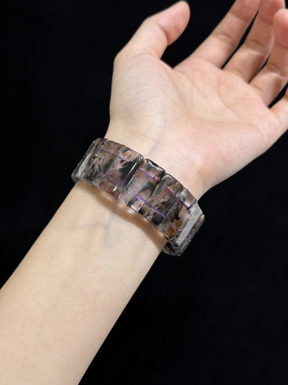 Woman wearing black dream phantom quartz rectangular slab bracelet, elegant dark crystal jewelry against black background