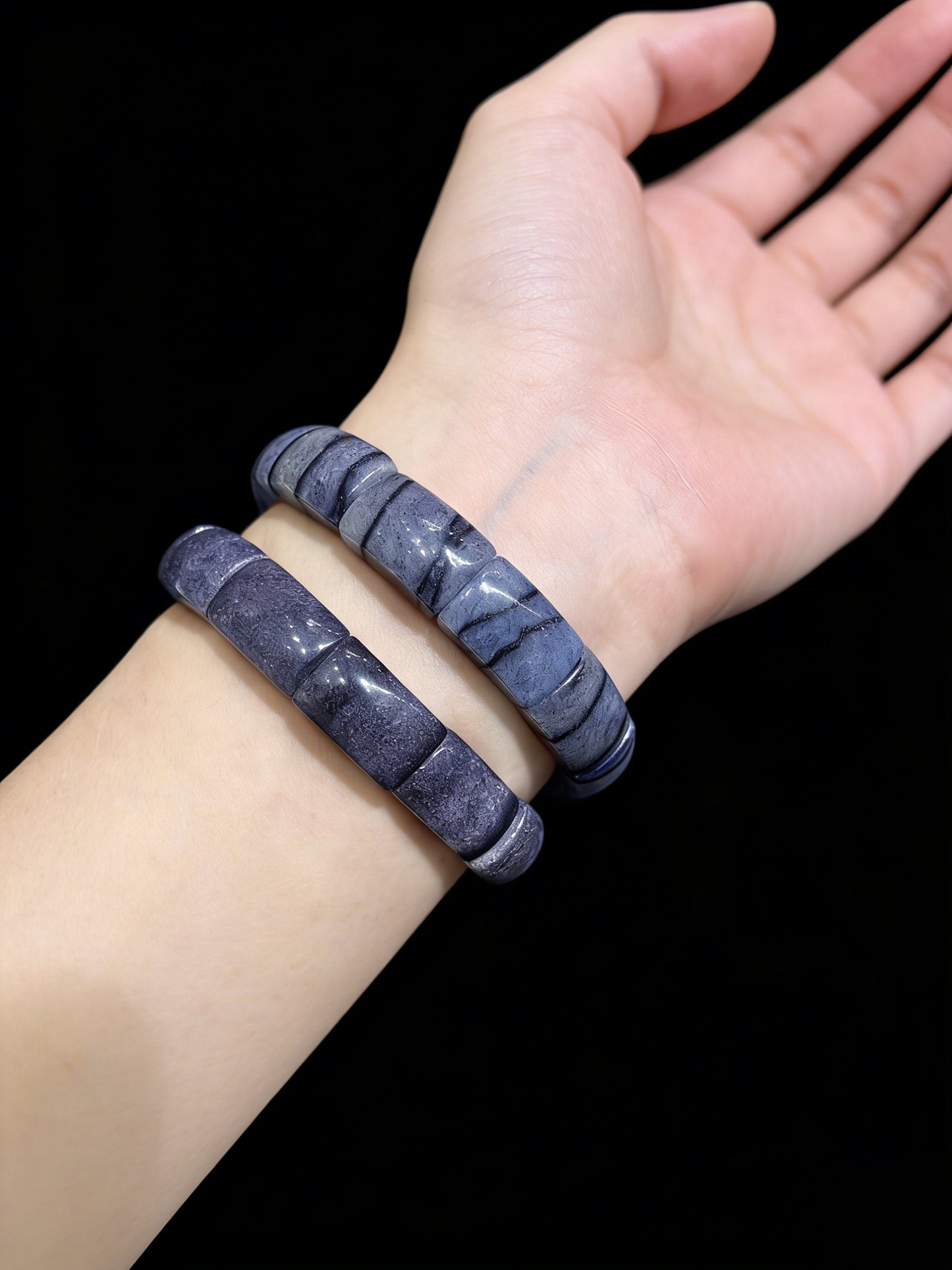 Woman wearing two blue aventurine square tablet bracelets, shimmering stackable unisex jewelry against black