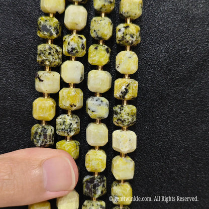 Fingers holding natural yellow jasper soft square gemstone block beads to show scale and proportion