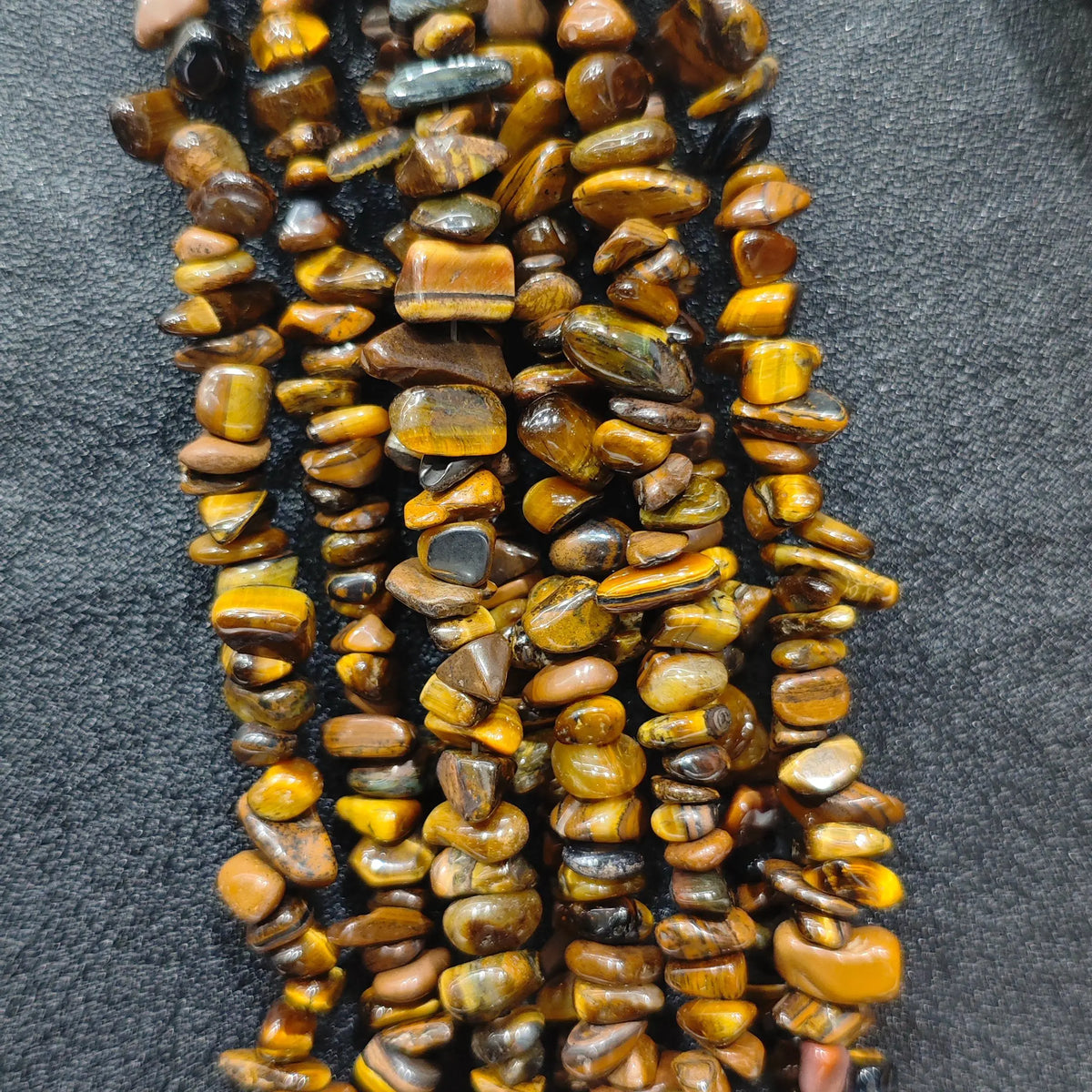 Close up of multi strands of natural yellow tiger eye 5-10mm irregular golden brown chatoyant chips[cite: 8]