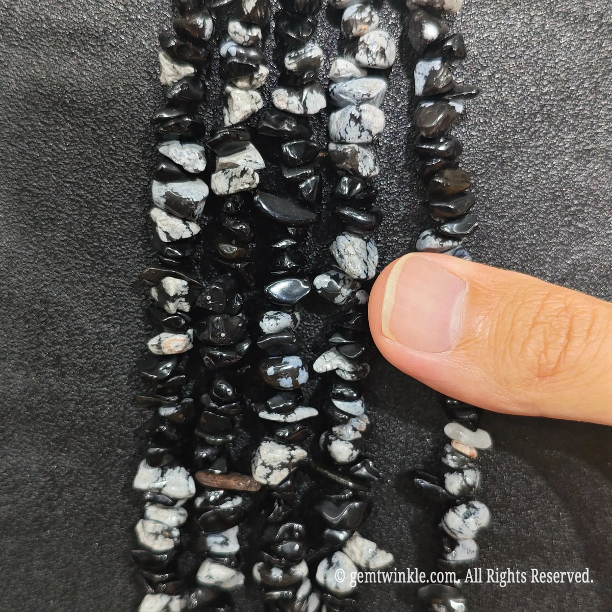 Close up hand holding natural zebra jasper stone chips displaying polished contrast surfaces and fine drill holes[cite: 9]