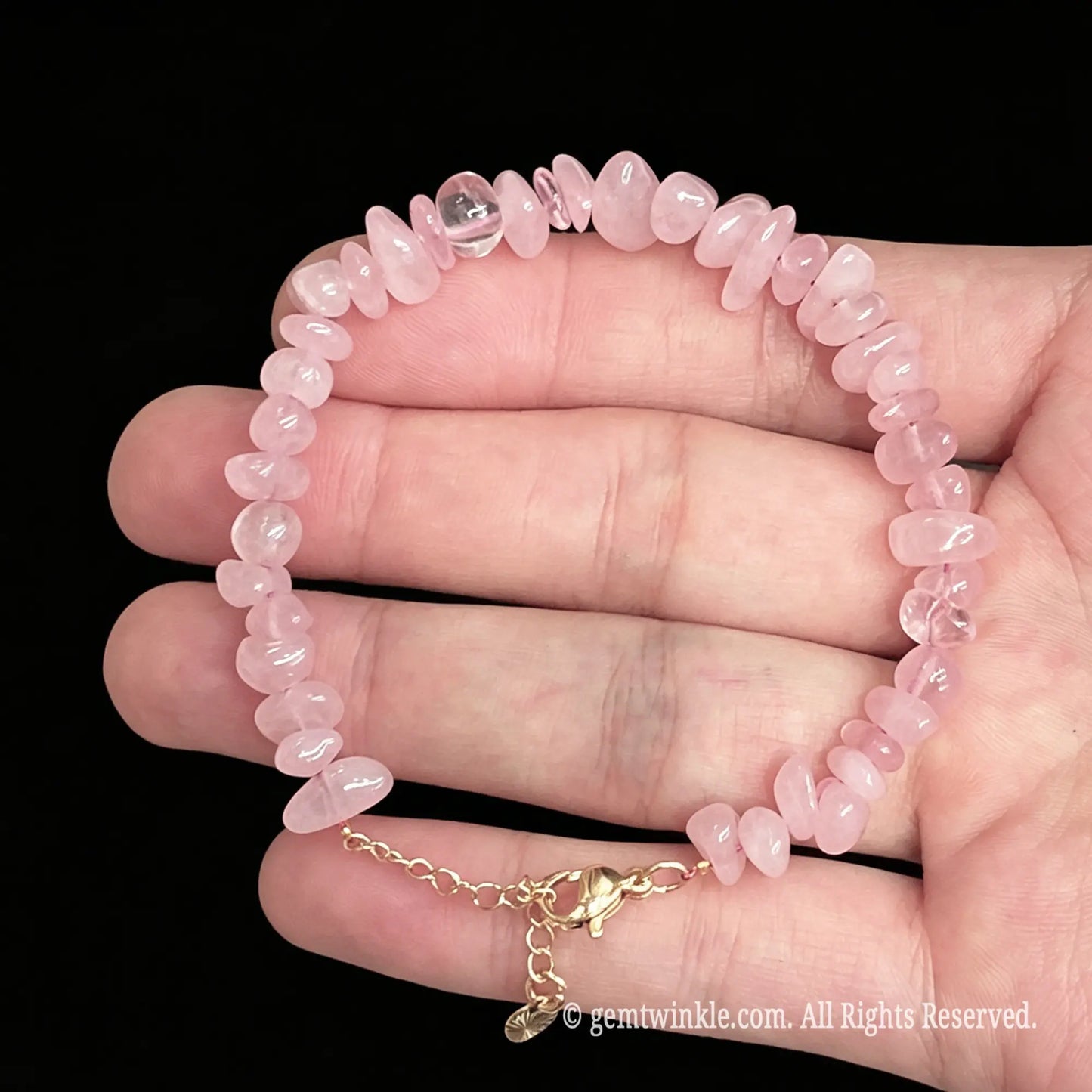 adjustable rose quartz chip bracelet in hand showing 15cm to 18cm flexible fit