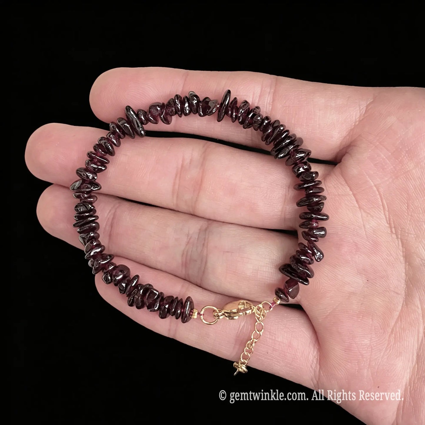 adjustable red garnet chip bracelet displaying gold tone lobster clasp and extender chain detail