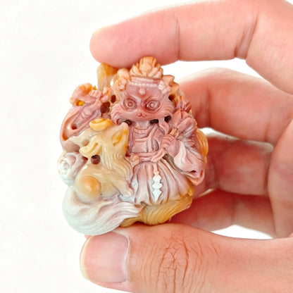 Handheld detailed view of natural Alashan agate carved celestial fox deity with spirit companion showing terracotta red and caramel color tones