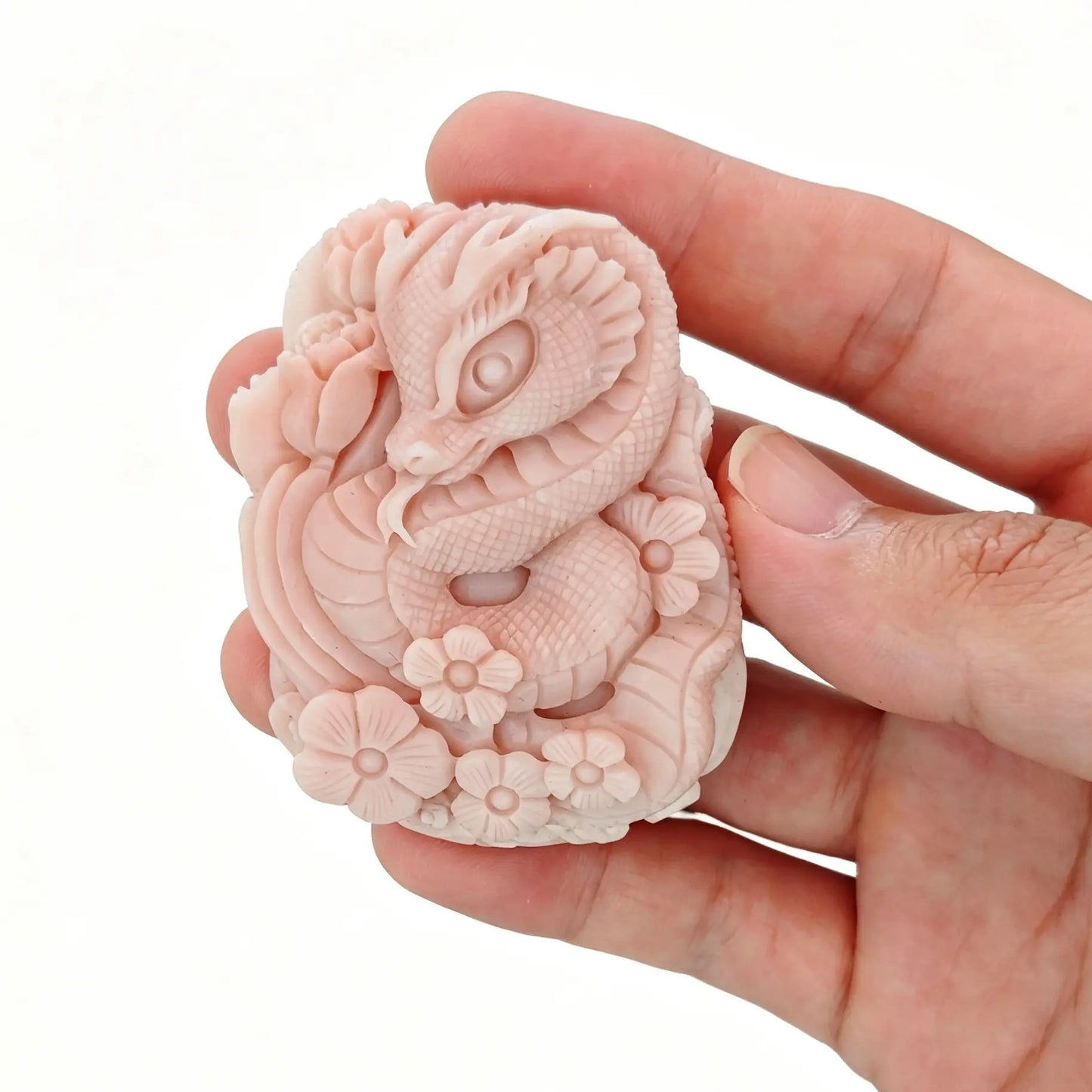 Handheld detailed view of natural dusty pink Alashan agate carved baby snake coiled in floral blossoms with flat back focal design