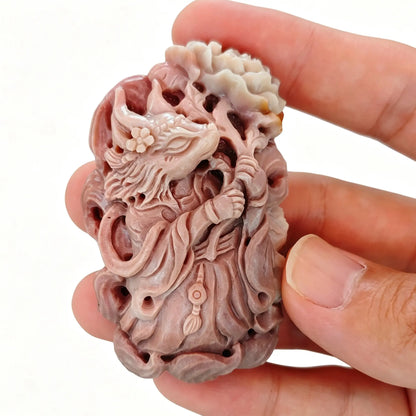 Handheld view of 5cm natural mauve pink Alashan agate carved fox fairy with hollowed openwork details and blooming peony blossom