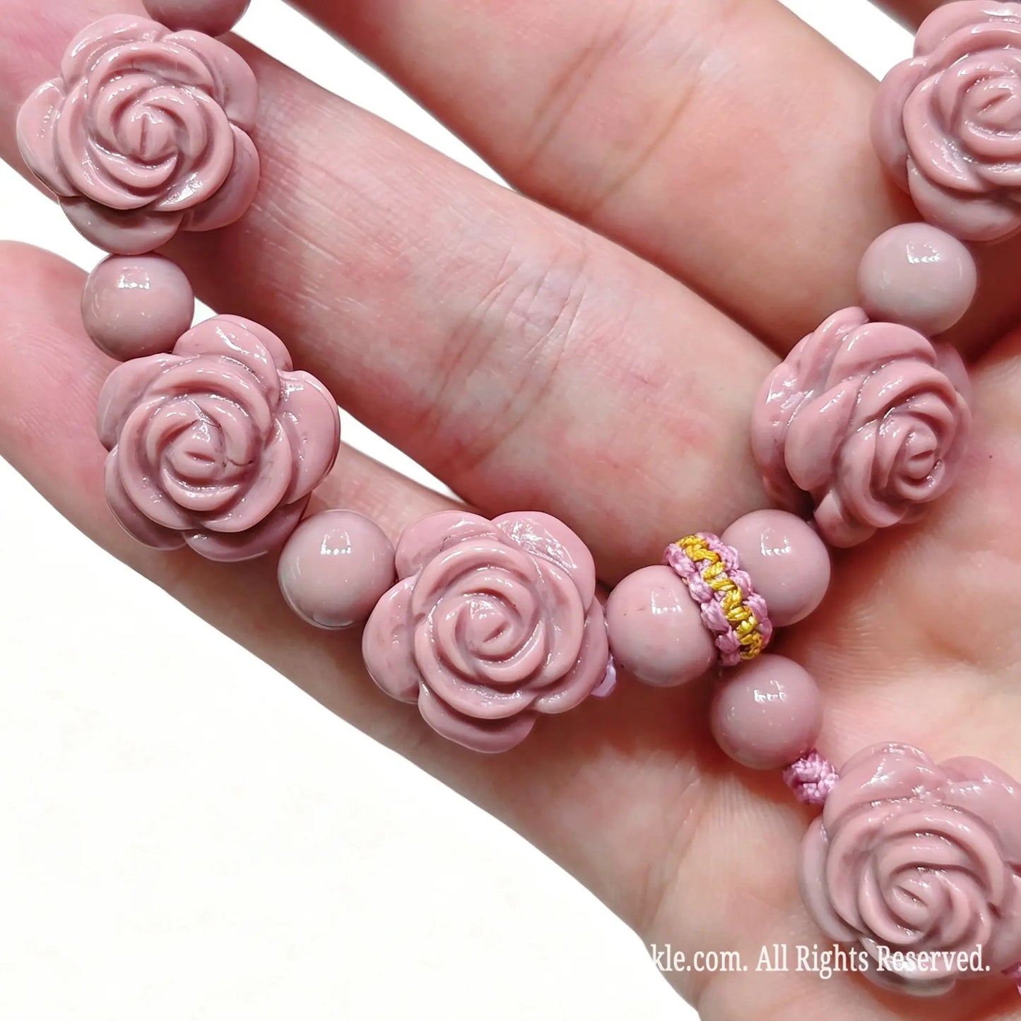 Detail view of decorative cord knotting and rose dangle tassel on pink Gobi agate bracelet