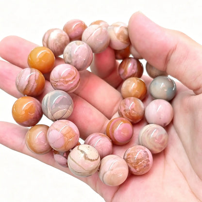 Main view of natural Alashan crackle agate round bead stretch bracelets stacked on open palm showing earthy pink and orange tones