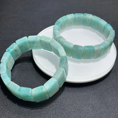 Two amazonite-bangle beaded bracelets on a white dish against a dark background