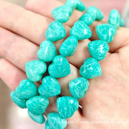 Top view close up of polished teal blue amazonite heart beads showing white matrix patterns