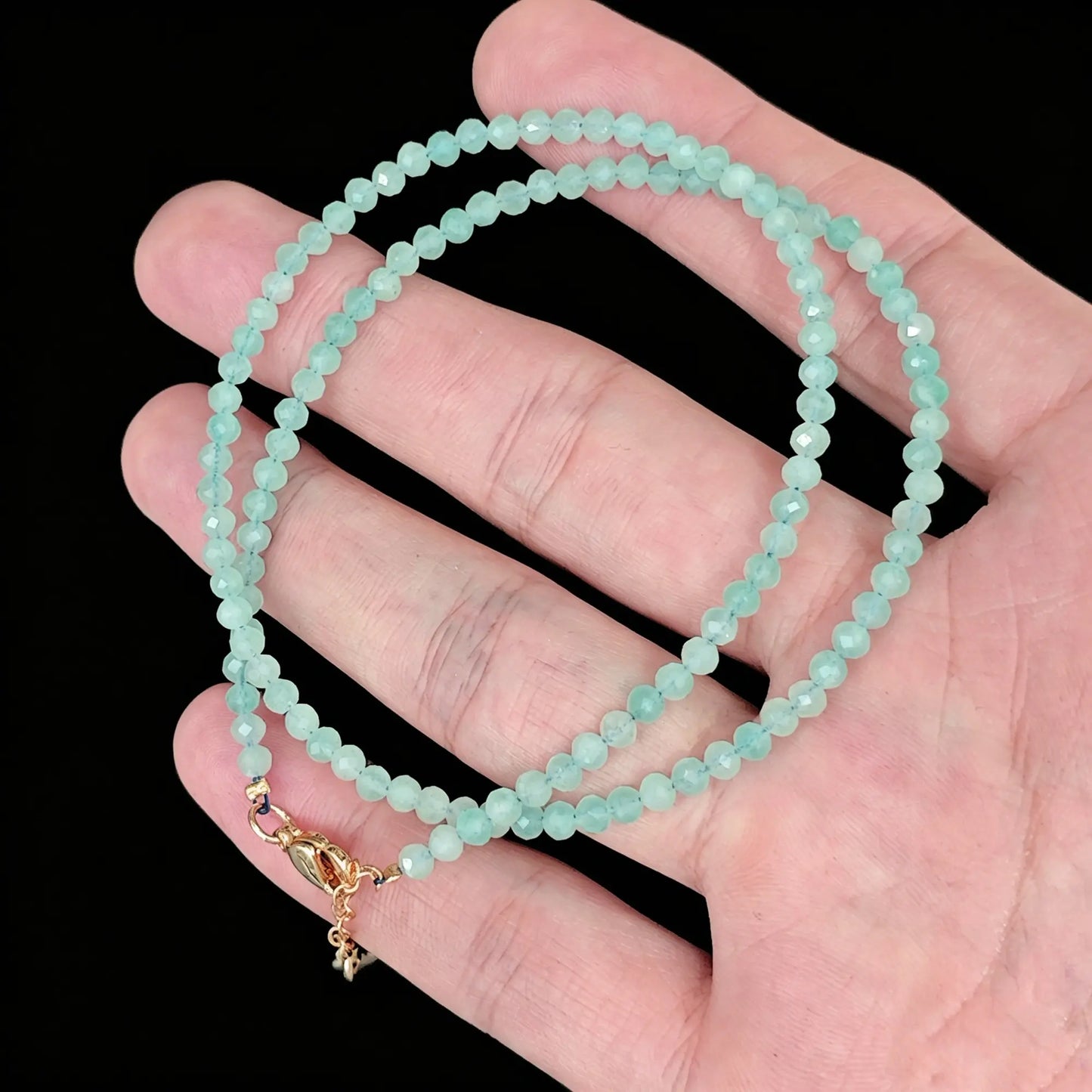 3-4mm amazonite faceted bead necklace coiled in hand showing turquoise green luster