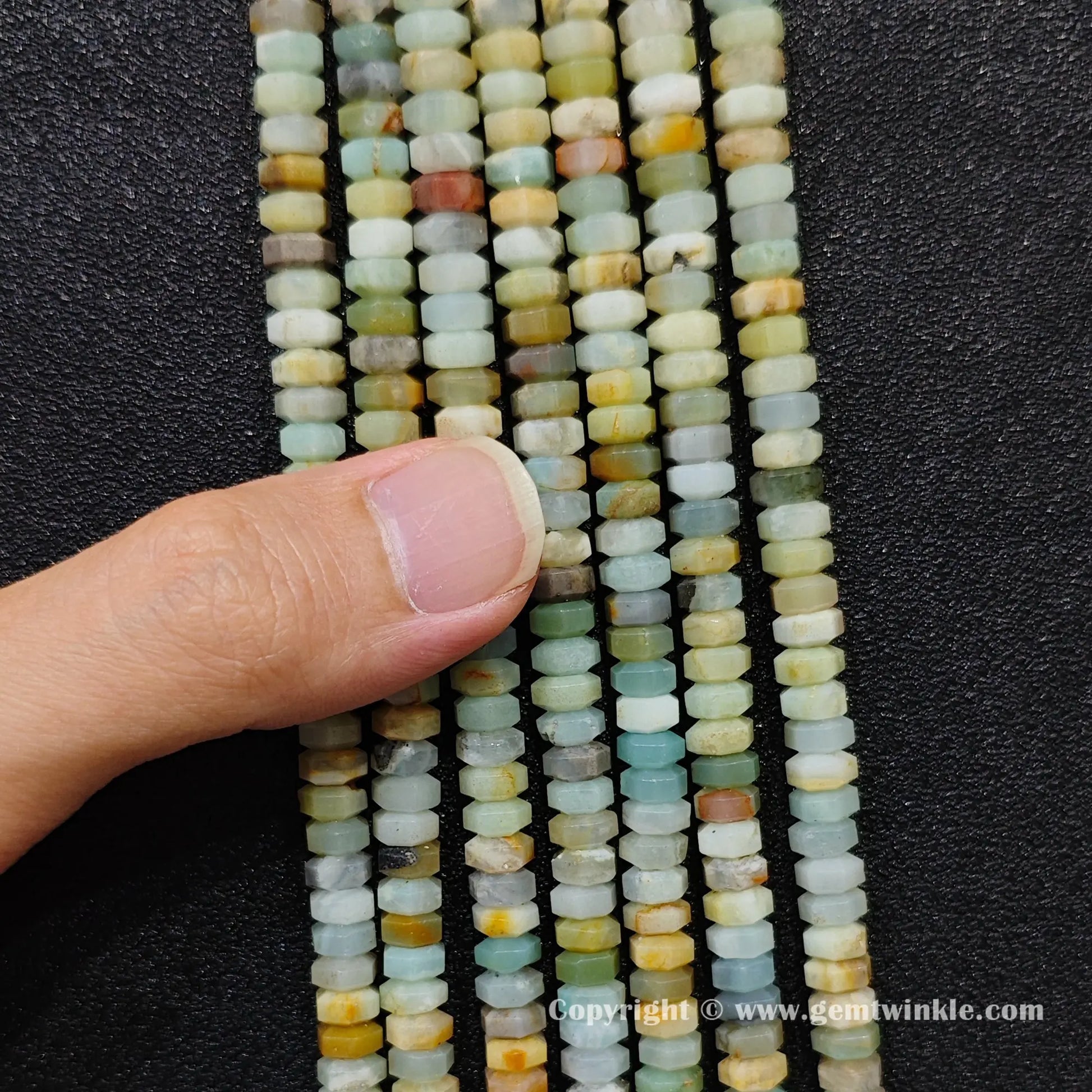 Close up view of 6x3mm amazonite faceted disc rondelle beads inspected on fingers for quality preview